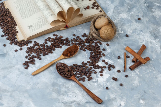 肉桂平铺咖啡豆 速溶咖啡 放在木制勺子里 上面有书 肉桂 饼干 绳子 背景是深蓝色和浅蓝色的大理石水平勺子想法