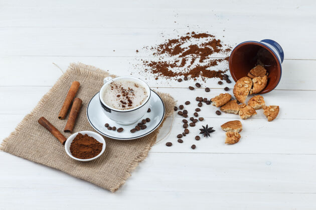 咖啡馆一些咖啡与咖啡豆 磨碎的咖啡 饼干 肉桂棒在一个木杯和一块布袋背景 高角度的看法块种子自然