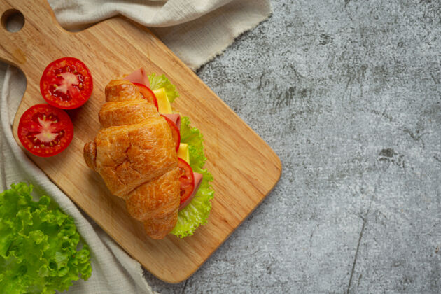 美味深色木制面上的羊角面包三明治西红柿生菜午餐