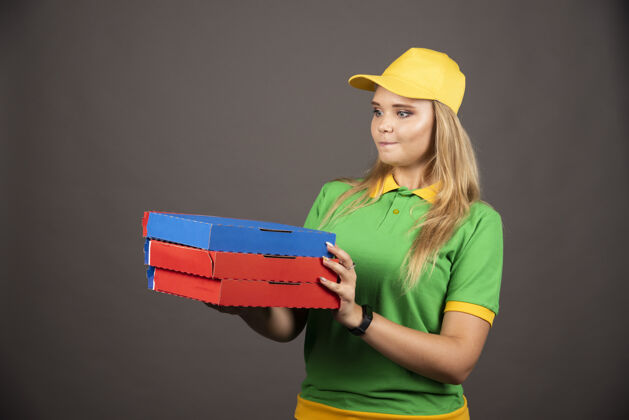 女士穿着制服拿着披萨纸板的女送货员女人帽子年轻