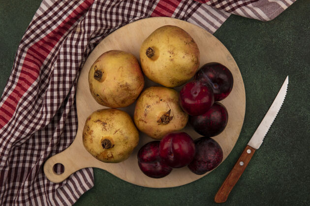 木材新鲜水果的俯视图 如Plots和石榴 放在绿色表面的格子布上的木制厨房板上衣服人检查