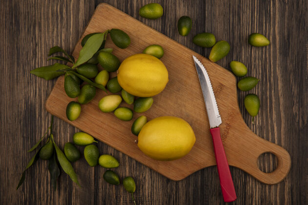 食物新鲜柑橘类水果的顶视图 如柠檬和金盏花在木制厨房板上 刀放在木制表面刀水果配料