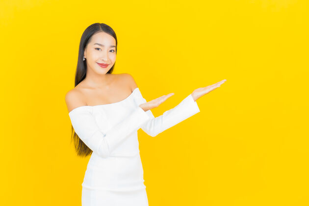 西装美丽的亚洲年轻商业女性在黄色墙壁上穿着白色裙子微笑的画像漂亮亚洲人美丽