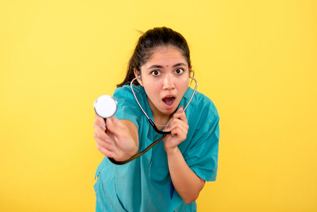 器械正面图是一位年轻的女医生 戴着黄色背景的听诊器背景年轻女医生医学