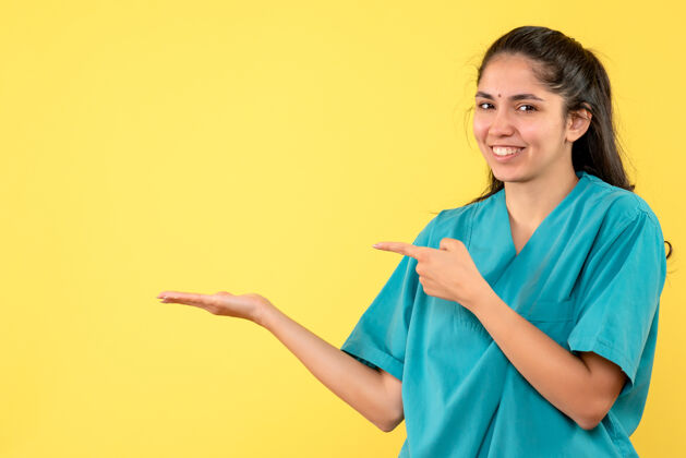 职业前视图微笑着身着制服的女医生站在黄色孤立的背景上肖像微笑正面