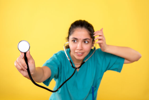 人物前视图微笑着穿着制服的女医生拿着听诊器在黄色的孤立背景上医疗正面手持