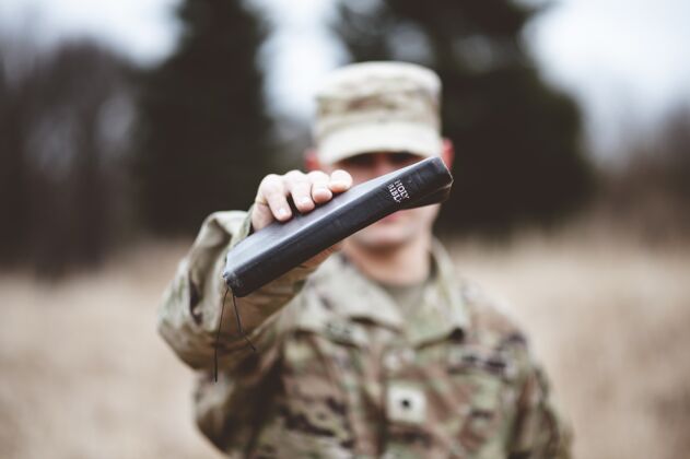 保卫一个美国士兵拿着圣经靠近镜头的选择性聚焦镜头保护精神国家