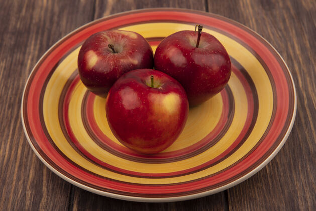 食品木头表面盘子上美味的红苹果俯视图木头盘子美味