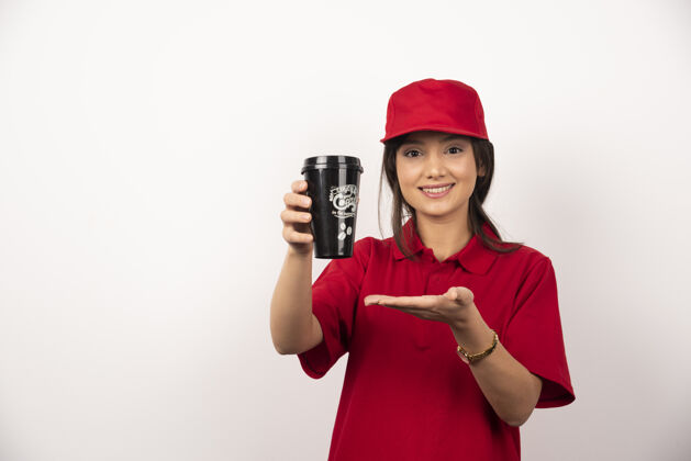 制服穿着红色制服的女人在白色背景上展示一杯咖啡手持雇员咖啡
