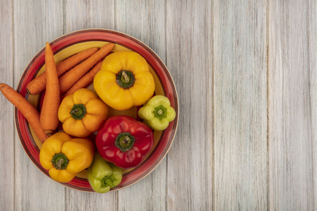 一餐顶视图五颜六色的甜椒与胡萝卜在一个灰色的木制表面复制空间盘子蔬菜自然辛辣