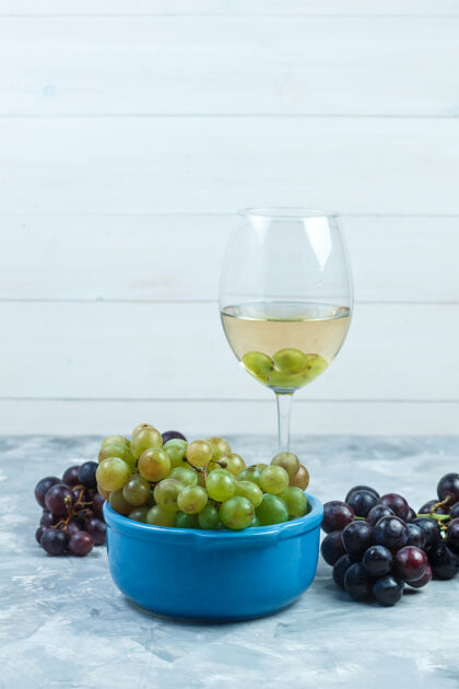 多汁一杯葡萄酒和葡萄放在一个碗里 背景是灰色和木制的侧视图串玻璃木材