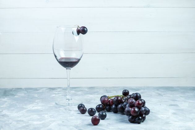 自然一杯葡萄酒和黑葡萄 背景为灰色和木质 侧面视图多汁果汁素食