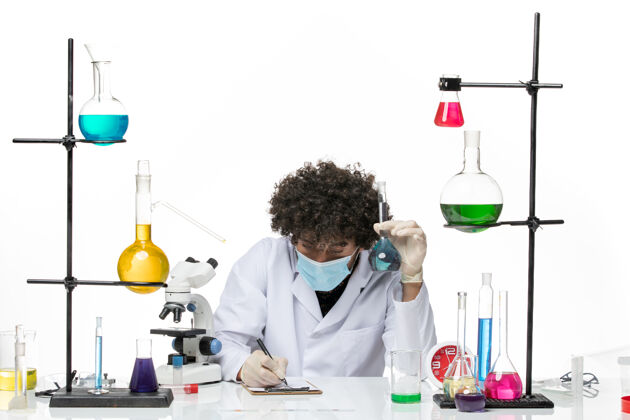 科学正面图：男化学家穿着白色医疗服 戴着口罩 拿着药水在空白处写字外套医学西装