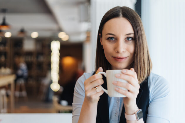 正面迷人的女性 带着可爱的微笑 一边喝着咖啡一边休息思考Wifi马克杯