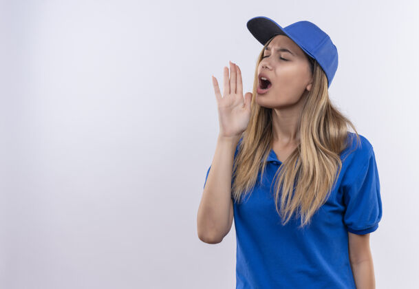 关门一个穿着蓝色制服 戴着帽子 闭着眼睛的年轻送货女孩 在白色的墙上喊着一个孤立的人 留着复印空间制服女孩年轻