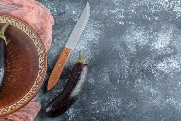 茄子灰色背景上的生茄子和刀的特写照片切碎成熟晚餐
