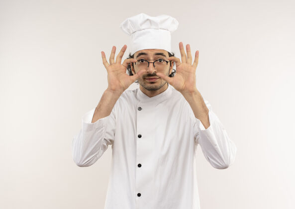 眼镜高兴的年轻男厨师穿着厨师制服 戴着眼镜把手放在隔离在白墙上的眼镜上请穿男性手