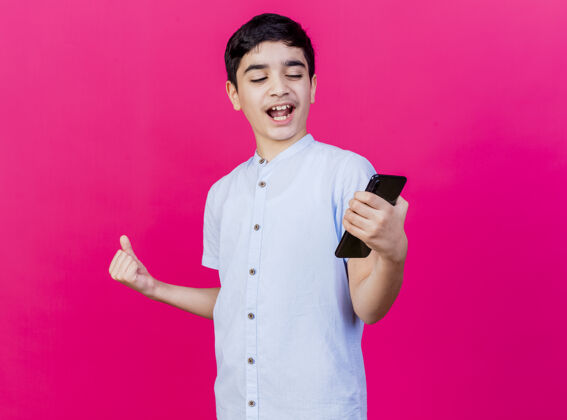表达快乐的年轻白人男孩抱着手机 看着手机做着“是”的手势孤立在深红色的墙上手势电话男人