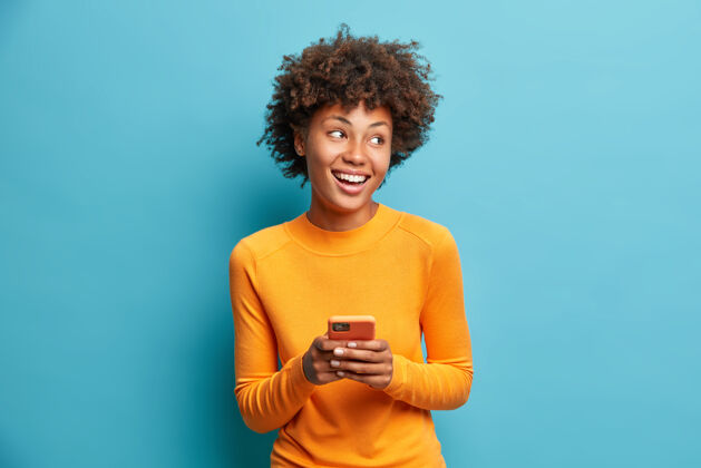 自然无忧无虑的快乐女学生使用手机进行在线远程教育愉快地看着一旁 微笑着在空闲时间上网浏览邮箱手机电话积极