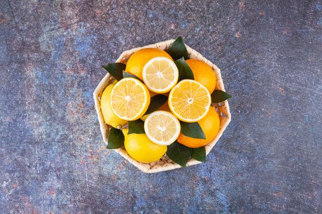 成熟柳条篮子里装满了新鲜柠檬 叶子放在大理石上有机多汁热带