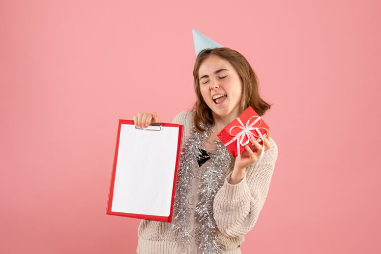 圣诞节年轻的女性拿着小圣诞礼物和粉红色的纸条举行女人礼物