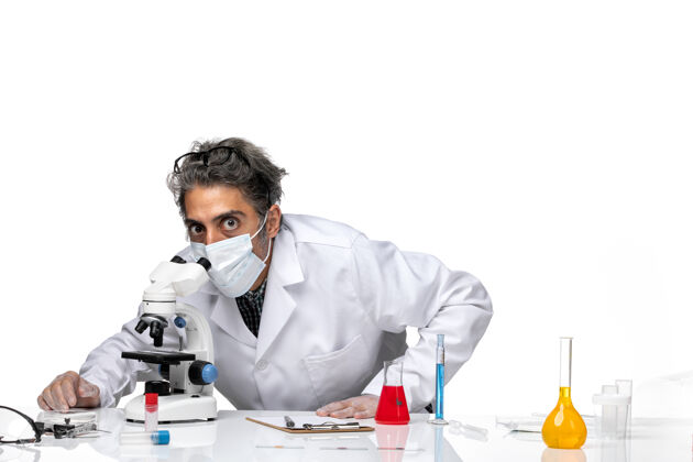 特殊前视图中年科学家穿着特殊的白色西装使用显微镜人化学医学