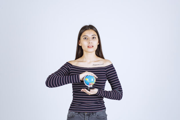 地图穿着条纹衬衫的年轻女子双手捧着一个迷你地球仪护理保护世界
