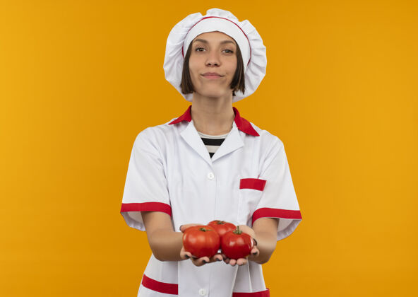 女性自信的年轻女厨师身着厨师制服 手里拿着西红柿 西红柿被隔离在橘子上 留有复印空间复制番茄制服