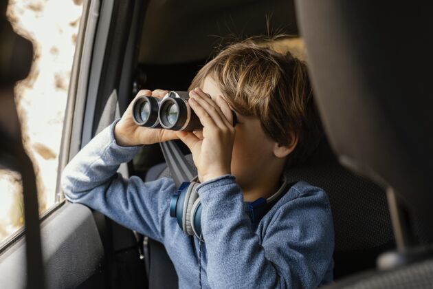 汽车旅行用望远镜给车里的小男孩画像男孩孩子旅行