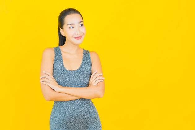 运动在黄色的墙上 描绘一位穿着运动服准备锻炼的美丽亚洲年轻女子训练健身房健身