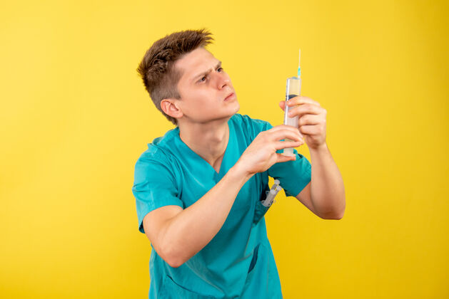 年轻男性医生正面图黄色背景上穿着医疗服拿着针剂的年轻男医生音乐家医院肖像