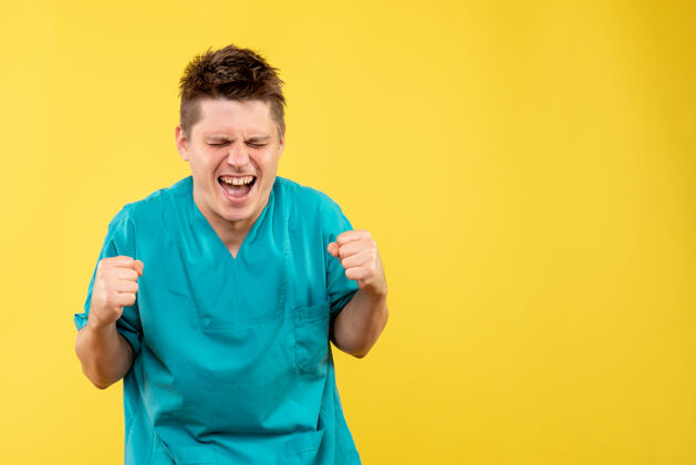 人正面图身着医疗服的年轻男医生在黄色背景上欢呼雀跃医院肖像男孩