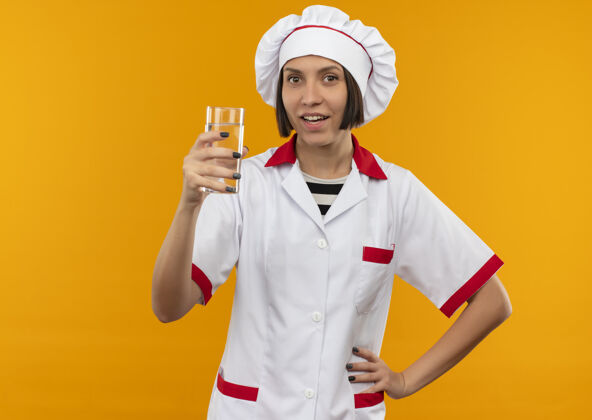 制服印象深刻的年轻女厨师在厨师制服举行杯水把手放在腰上孤立的橙色与复制空间印象复制腰