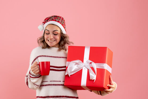 举行年轻的女性拿着圣诞礼物和一杯粉红色的茶女人礼物盒子