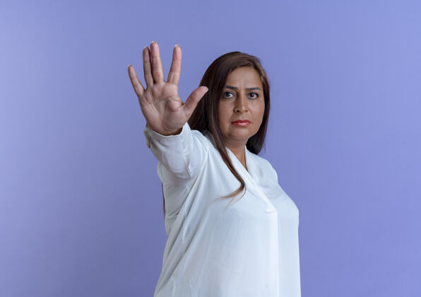 停止严格随意的白种中年妇女显示停止手势孤立在蓝色墙上严格中年手势