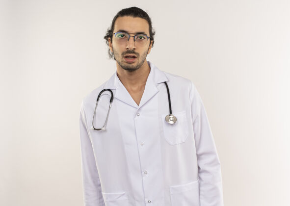 医生惊讶的年轻男医生戴着眼镜 穿着白色长袍 听诊器放在隔离的白墙上 留着复印空间光学年轻长袍
