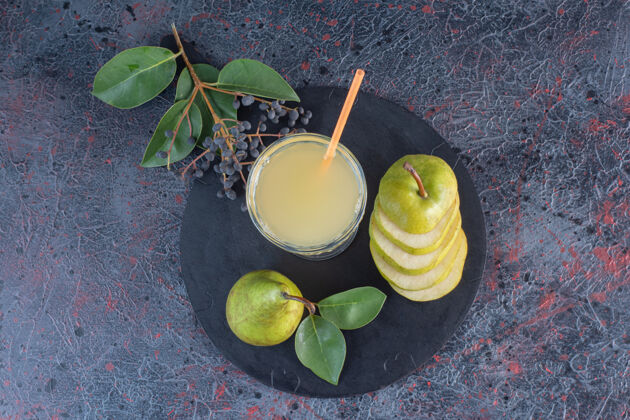 特写顶视图一杯梨汁和绿色的梨片放在木板上美味切片美味