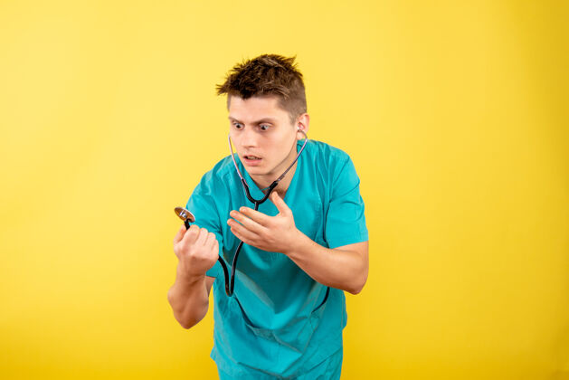 药正面图黄色桌子上穿着医疗服 带听诊器的年轻男医生成人高尔夫球手桌子