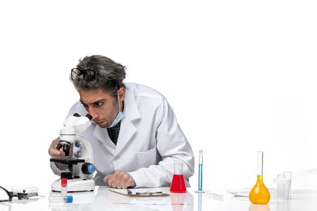 化学穿着白色医疗服的中年科学家使用显微镜的正视图人视图显微镜