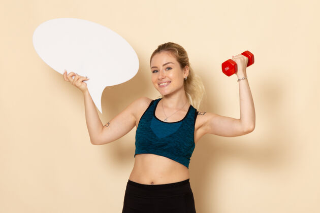 健康正面图身穿运动装的年轻女性手持哑铃和白色的演讲泡泡体重健身运动