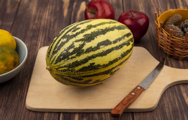 夏天顶视图新鲜的哈密瓜在一个木制的厨房板与刀与苹果隔离在木墙上哈密瓜顶部木板