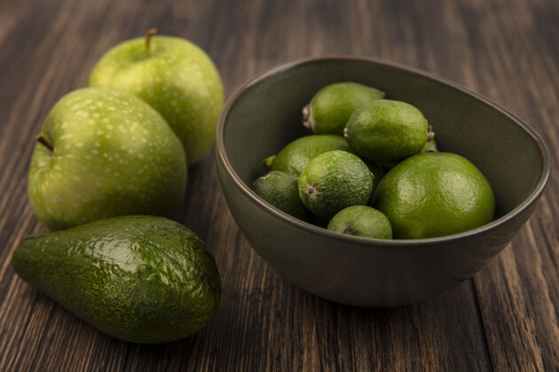 木头绿色熟透的菲乔斯（feijoas）的俯视图 柠檬放在一个碗里 绿色的苹果和鳄梨被隔离在一堵木墙上鳄梨风景顶