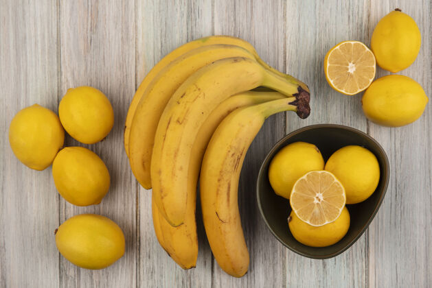 水果新鲜多汁的柠檬在碗上的俯视图 香蕉和柠檬被隔离在灰色的木墙上顶部多汁新鲜