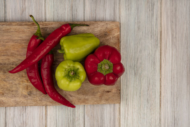胡椒顶视图新鲜的彩色铃铛和辣椒在一个木制厨房板上的灰色木制墙壁与复制空间蔬菜有机食物