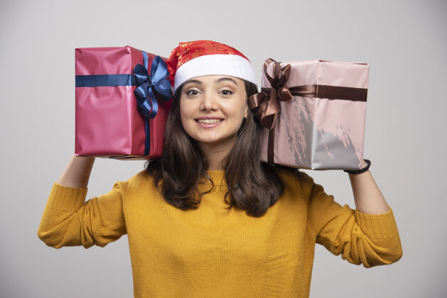 圣诞老人戴圣诞帽的年轻女子手里拿着礼品盒女性女人女士
