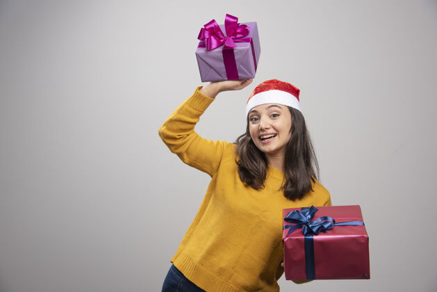 女性戴着圣诞帽拿着礼盒的年轻女子微笑惊喜人