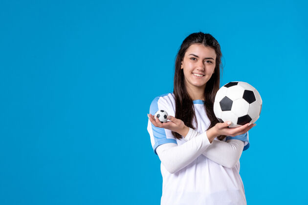 比赛前视图：蓝色墙上有足球的年轻女性青年足球前面