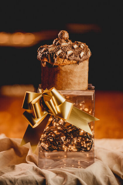 礼物垂直特写镜头浪漫的盒子与灯光 一条金丝带 和松饼单人闪亮食物