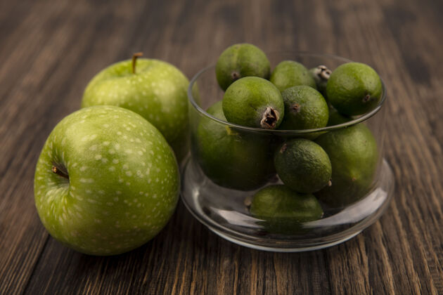 碗在玻璃碗上的新鲜成熟的feijoas的俯视图 绿色的苹果被隔离在木墙上视野苹果新鲜