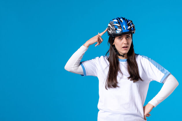 运动前视图穿着运动服的年轻女性 蓝色墙上戴着头盔视图帽子前面